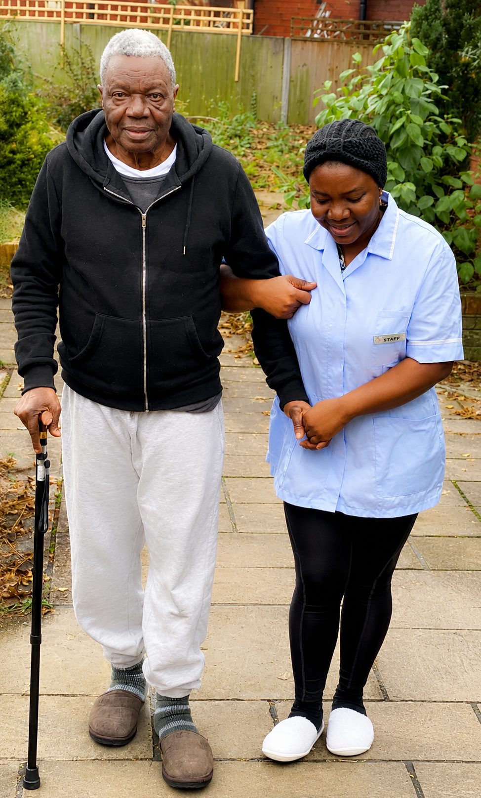 An Angeliquecare carer supporting an elderly man walking outdoors with his stick